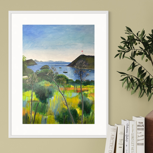 After the Rain landscape by Elaine Boylan. View from Gümüşlük on the Bodrum Peninsula in Turkey. Pale blue sky over the Aegean sea, hill with flag pole flying the Turkish flag, field in the foreground, Greek islands in the distance. Colours are mainly greens, golds and blues. High quality giclée print on fine art paper with mount/mat and white frame. Print is shown on a pale gold wall above a white console table with books and vase.