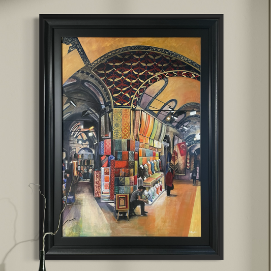 Framed painting of the interior of the Grand Bazaar in Istanbul on a wall above a wooden shelf.